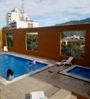 Zona social del Edificio Fontainebleau con piscina para adultos y niños, rodeada de sillas y vista a la ciudad.